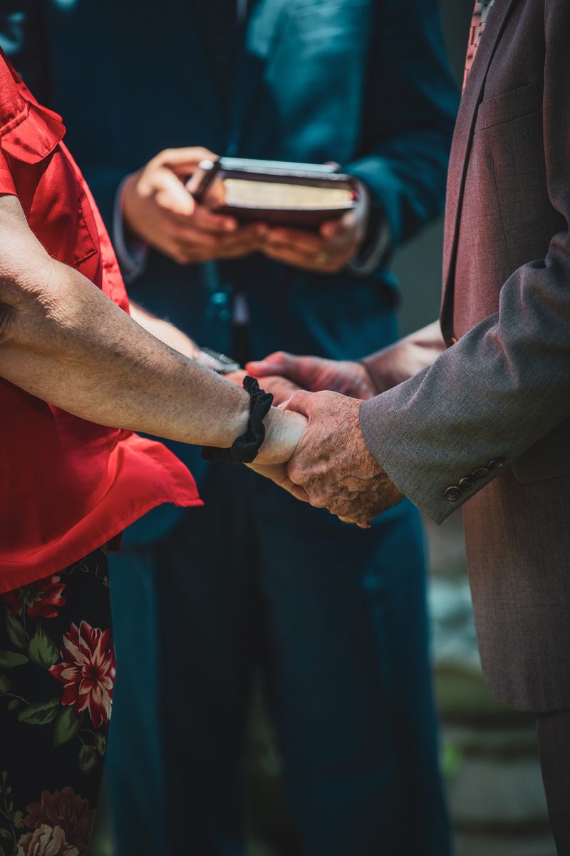 Couple exchanging vows with an officiant holding a Bible
