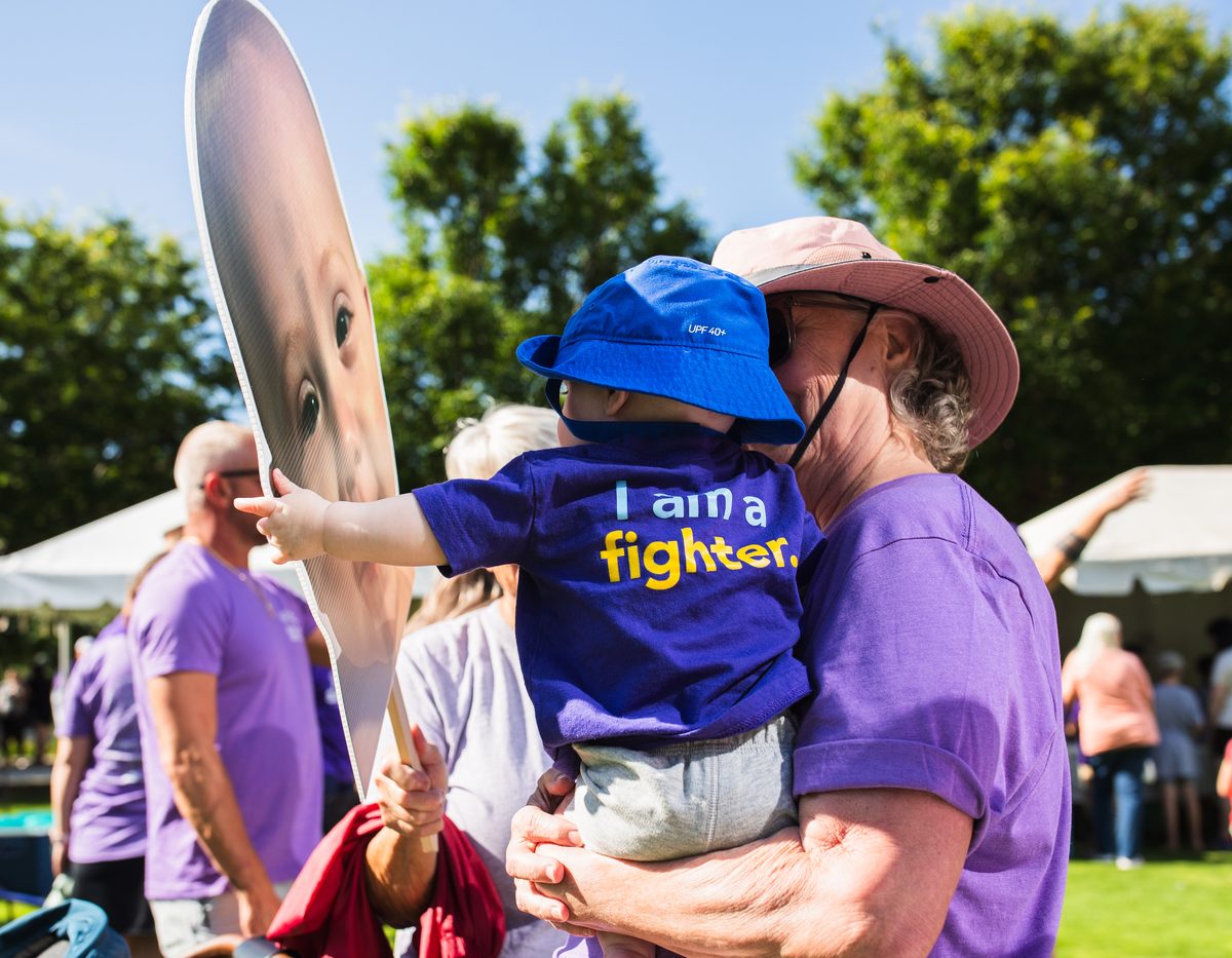 Crowd cheering and holding signs at a charity walk event