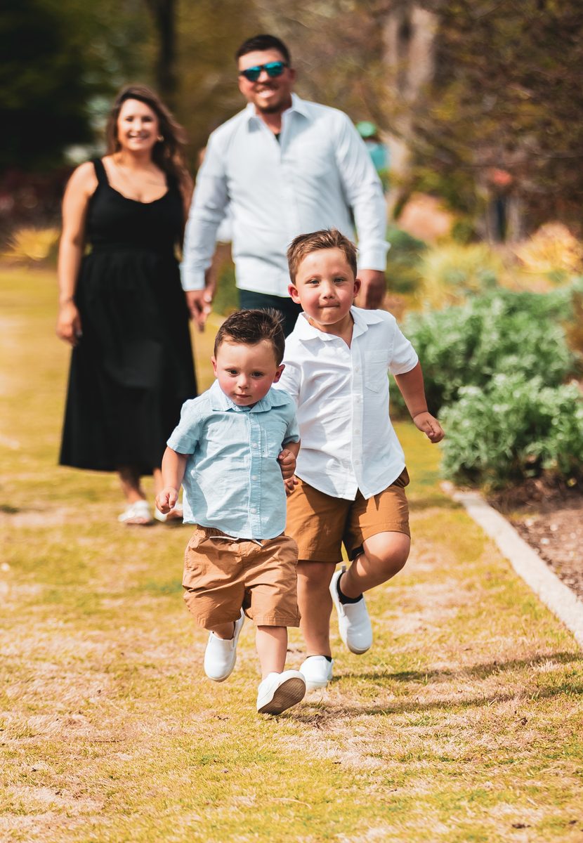 Two young boys running toward the camera with parents behind them
